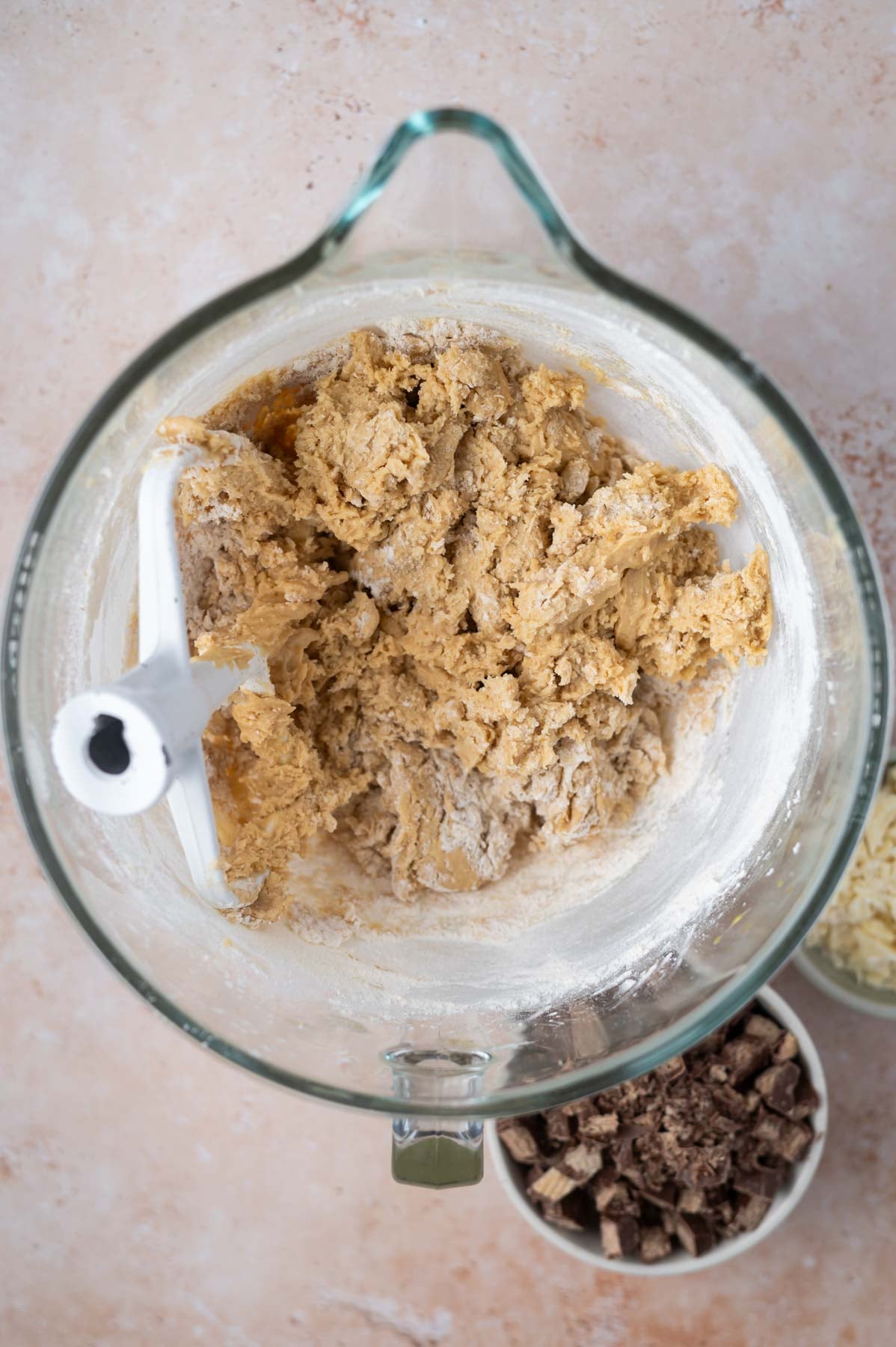 flour added to cookie dough in a mixing bowl with some large streaks of flour remaining