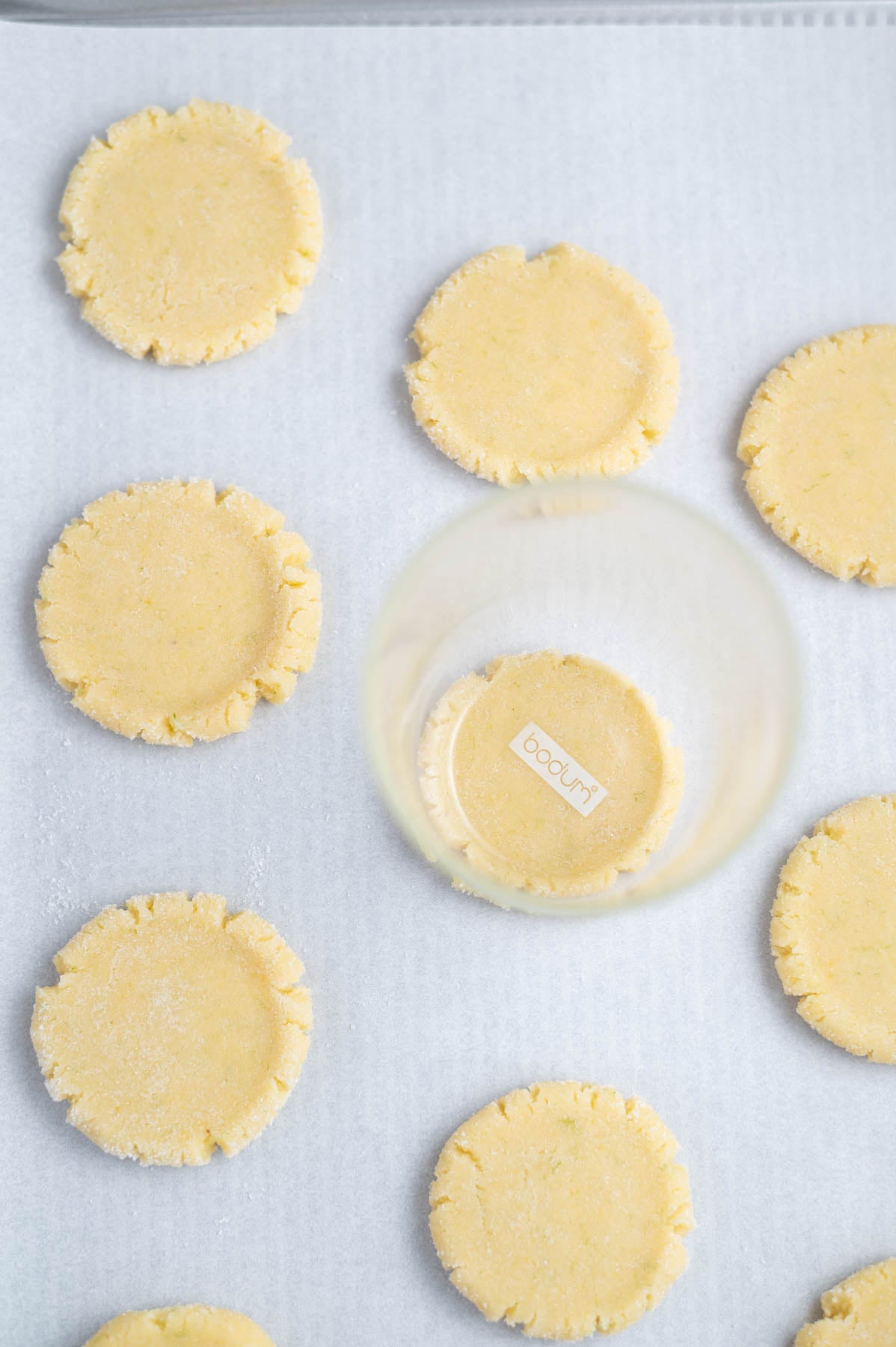 cookie dough flattened with a glass on a parchment lined baking pan