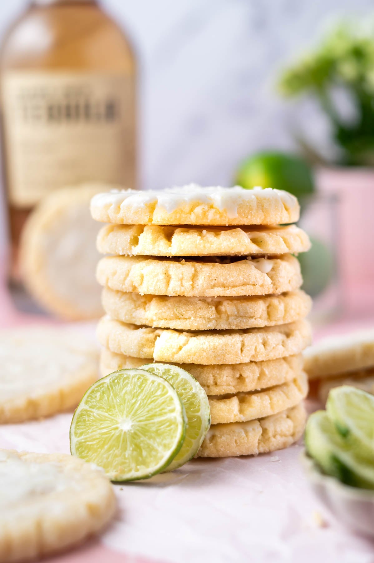 stack of cookies with lime slices and a bottle of tequila in the background