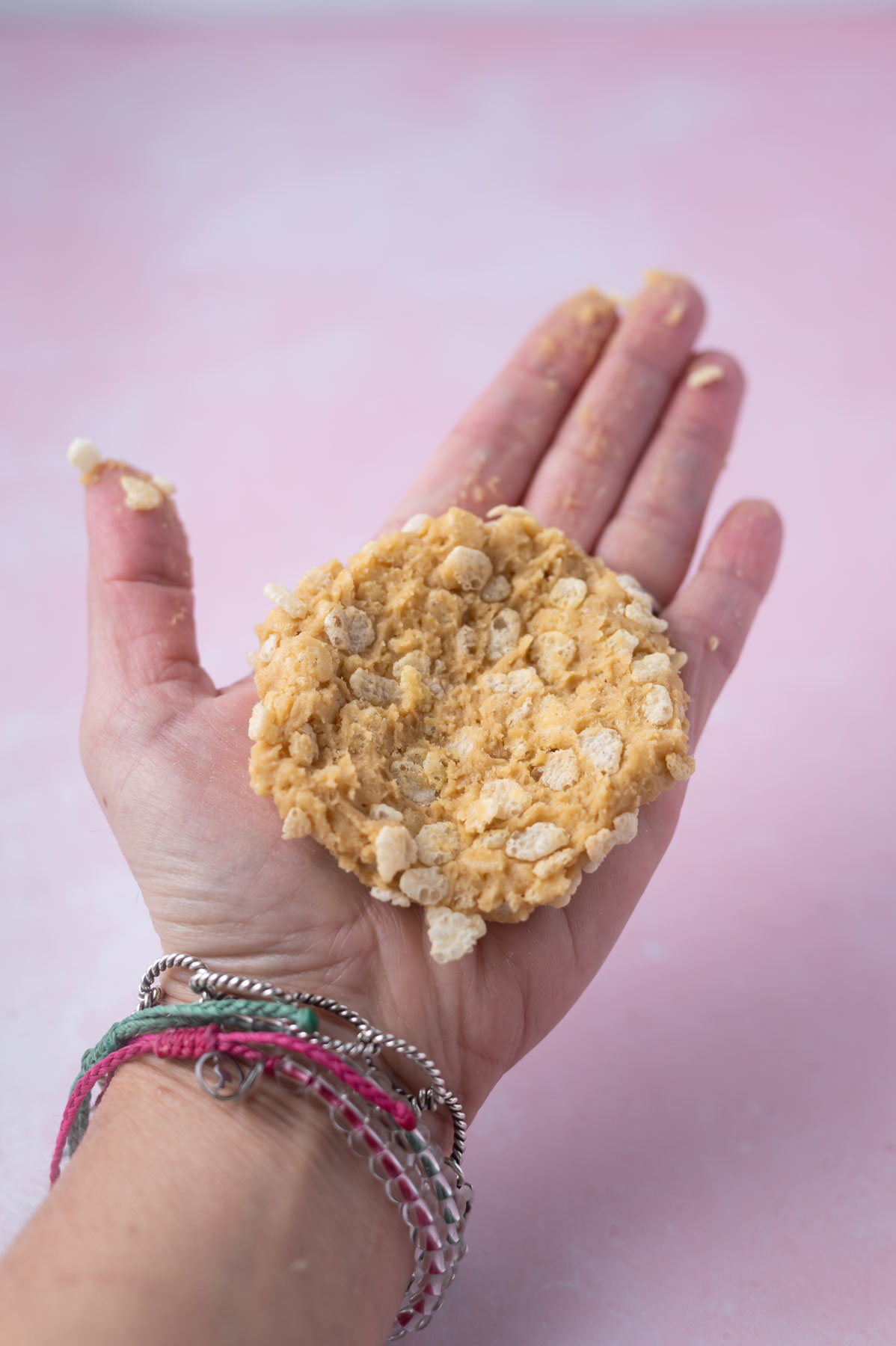 hand holding a flattened rice crispy cookie dough ball