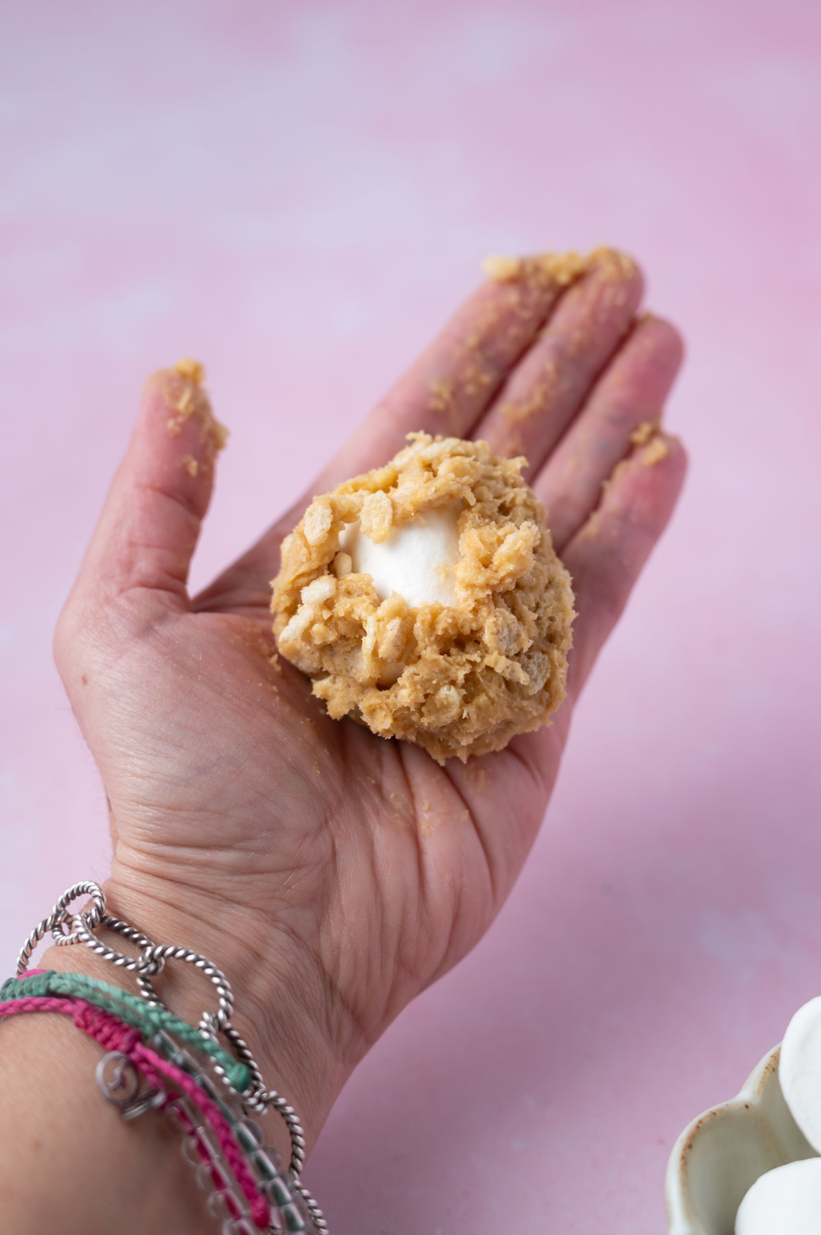 cookie dough wrapped around a large marshmallow in a hand