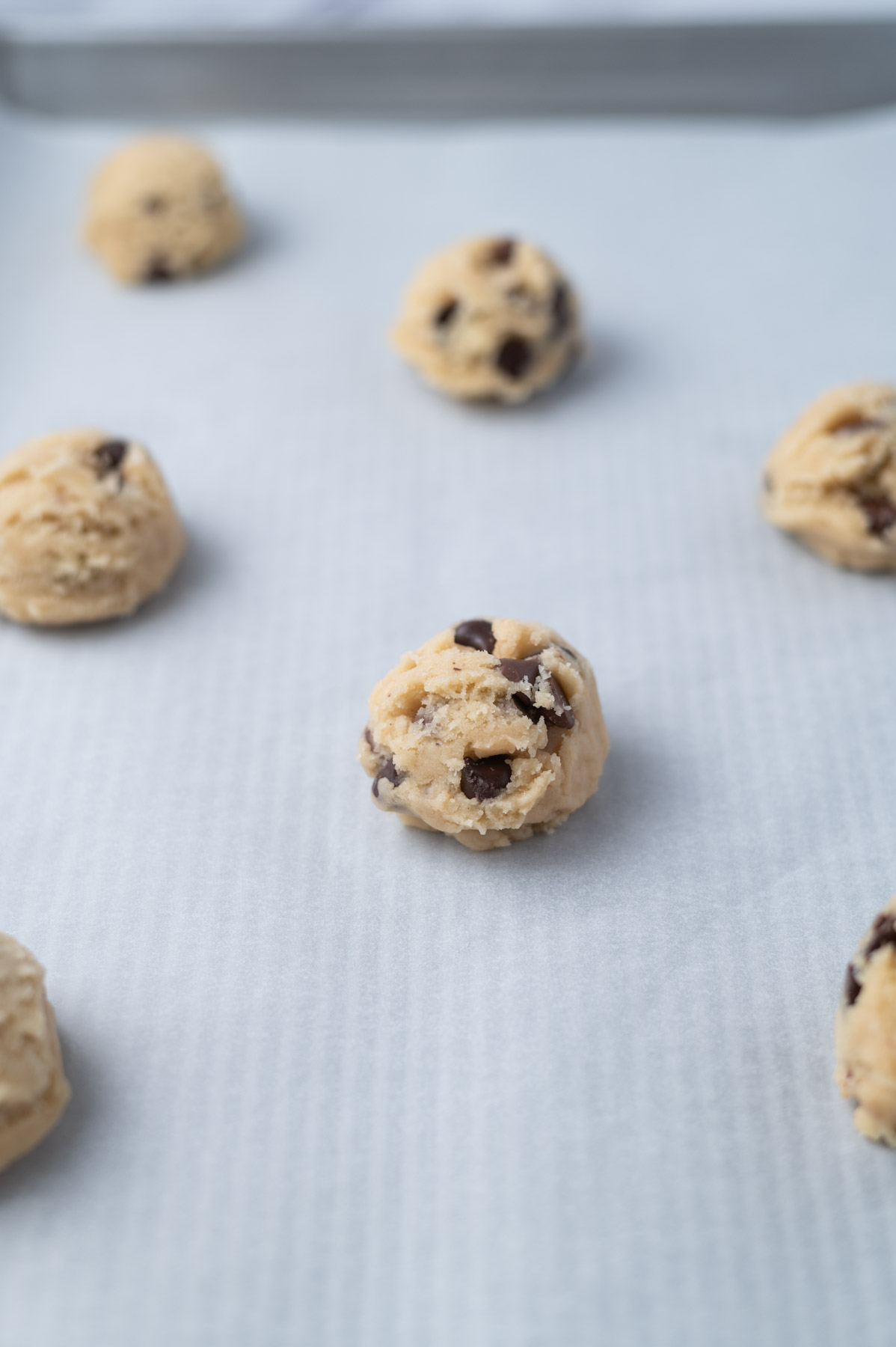 chocolate chip cookie dough balls on a parchment lined baking sheet