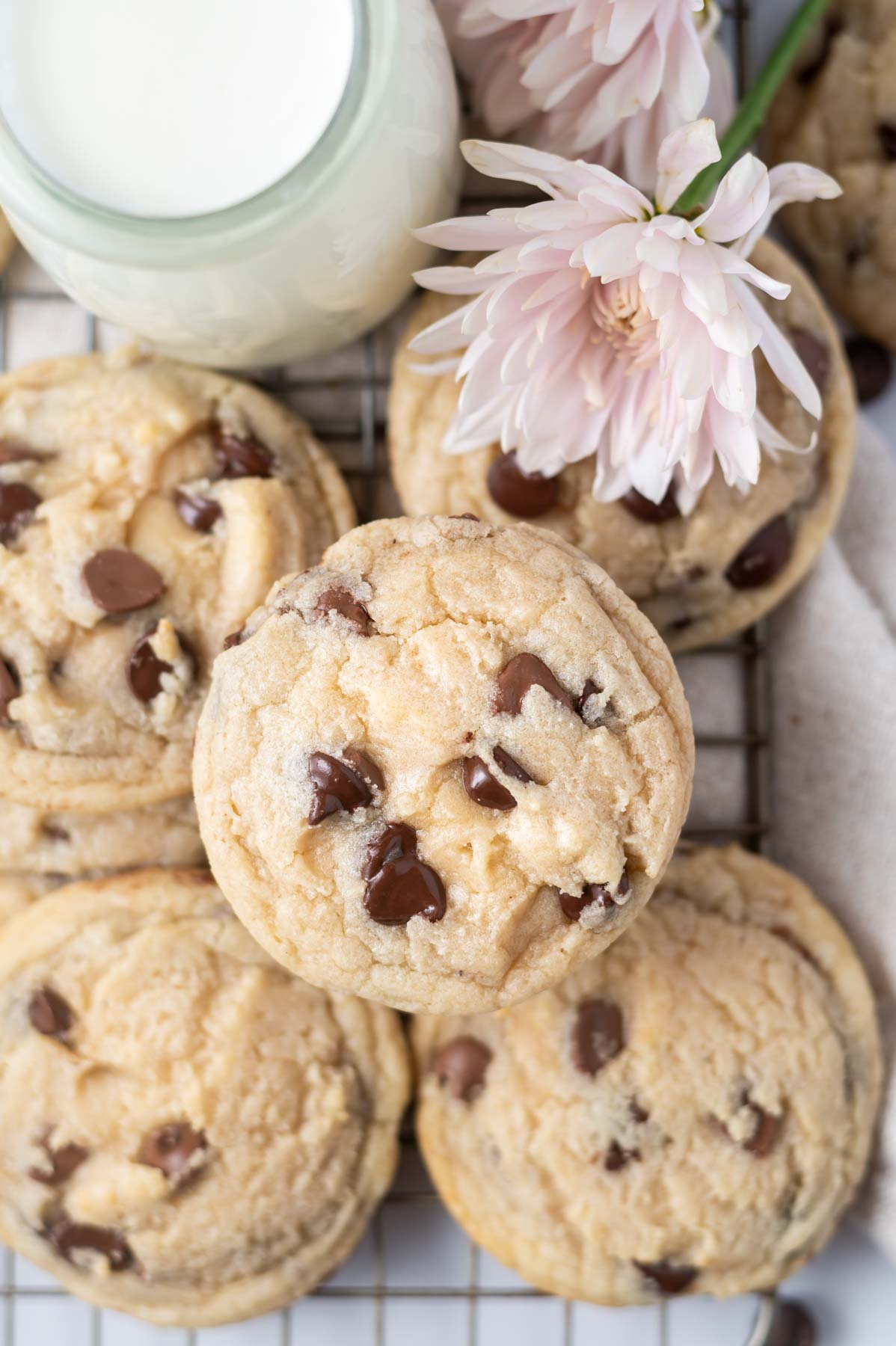 overhead look at cookies on a cooling rack with a glass of milk and pink flowers