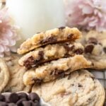 stack of broken chocolate chip cookies without brown sugar with a glass of milk and pink flowers