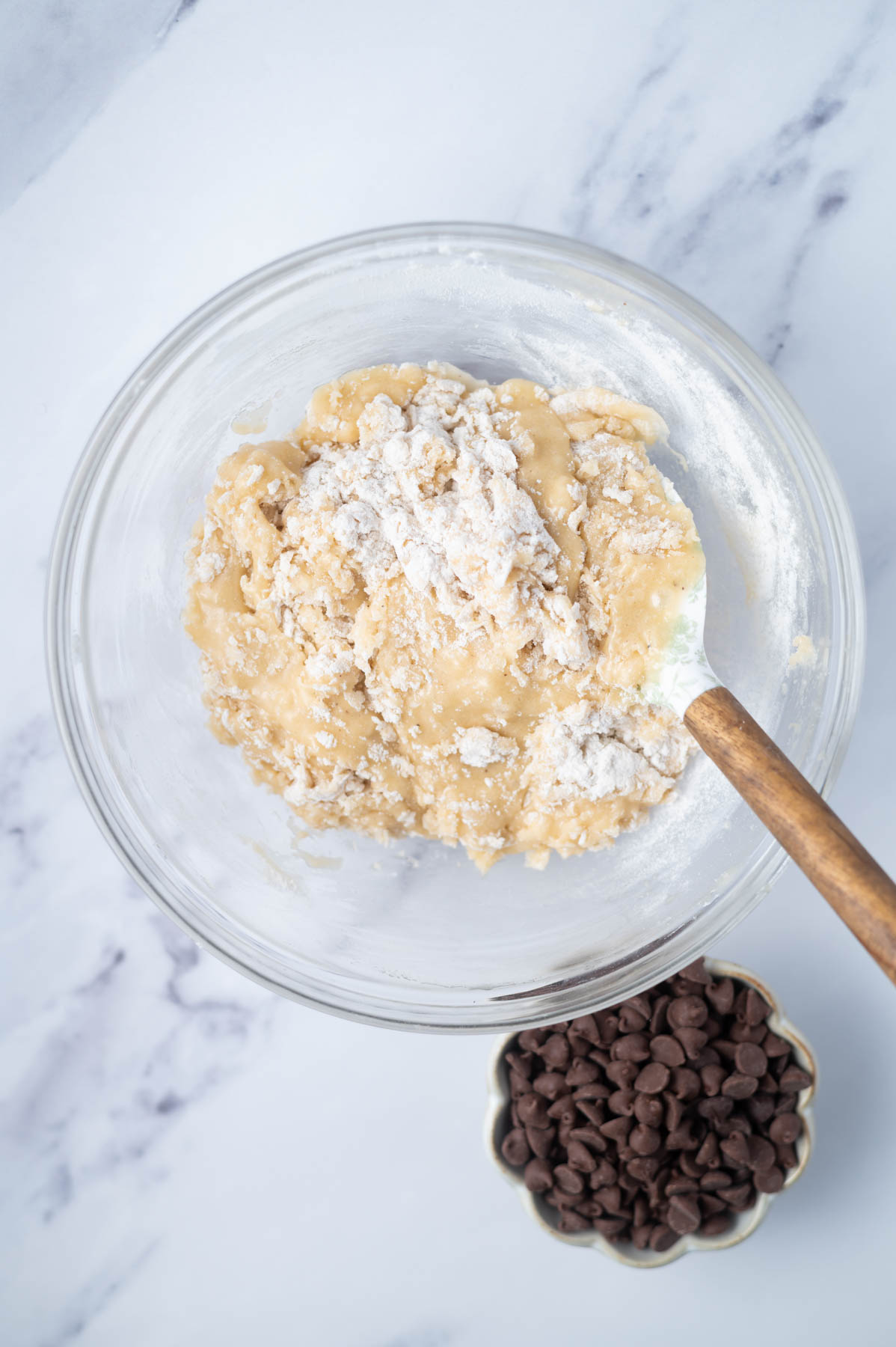 cookie dough in a bowl with a spatula showing large streaks of flour