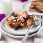 slice of cinnamon focaccia on a plate with a fork with a glass of milk in the background