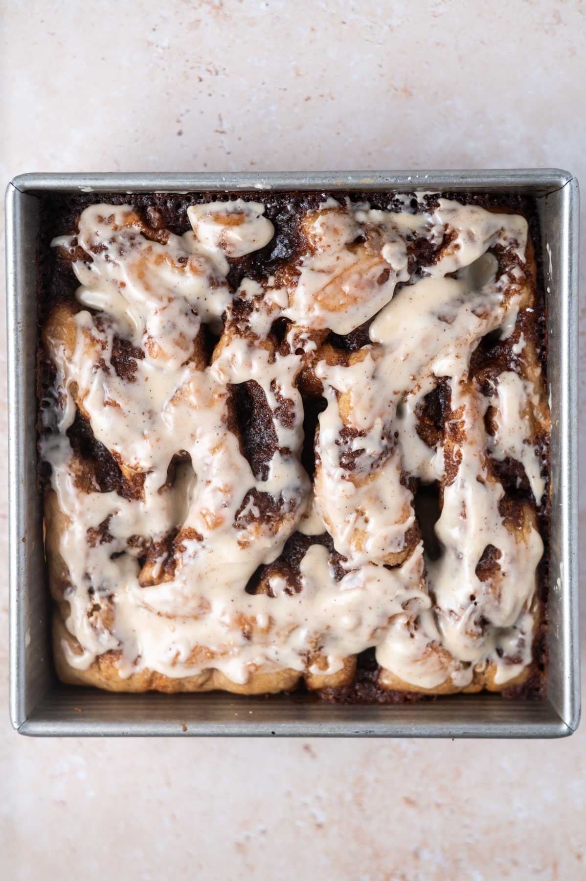 vanilla icing glaze over baked bread in a baking pan