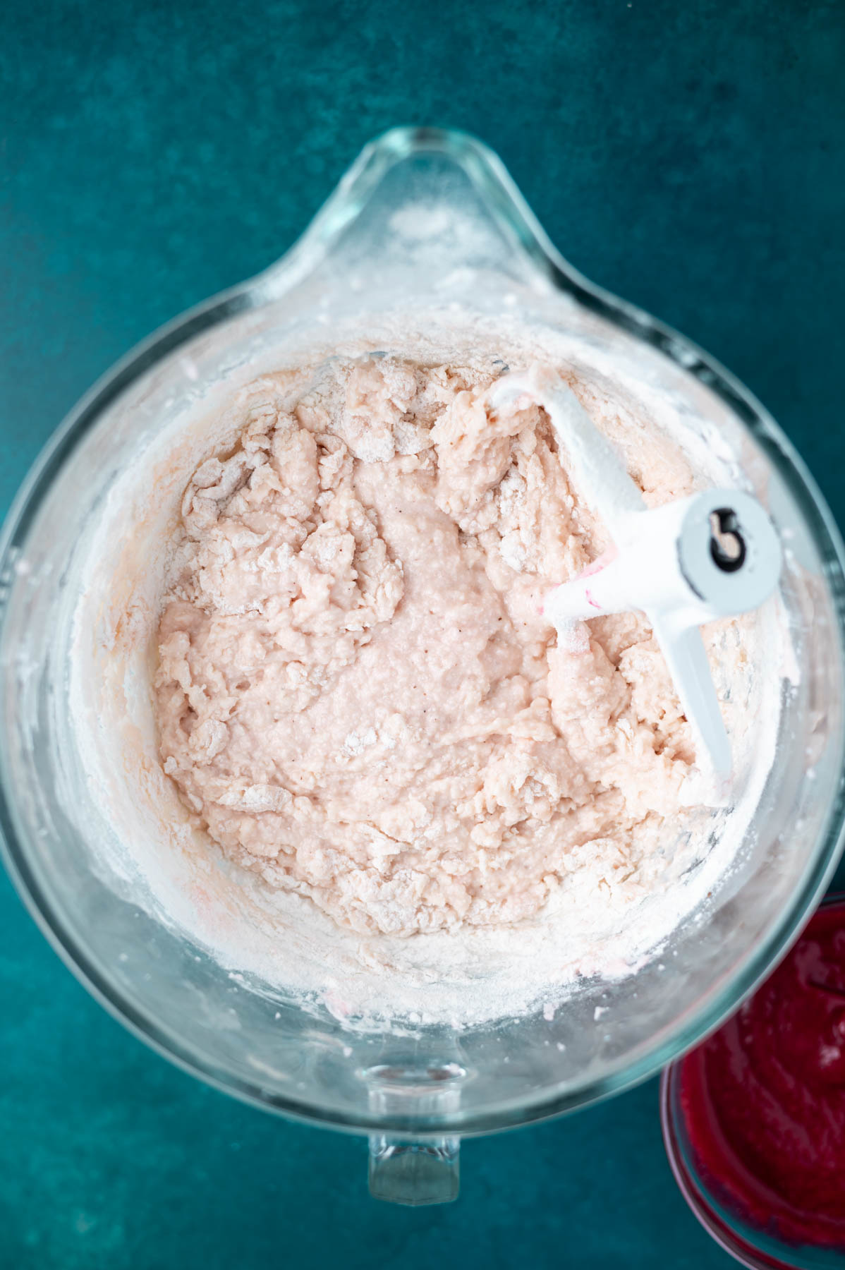 cake batter in a mixing bowl with large streaks of flour remaining
