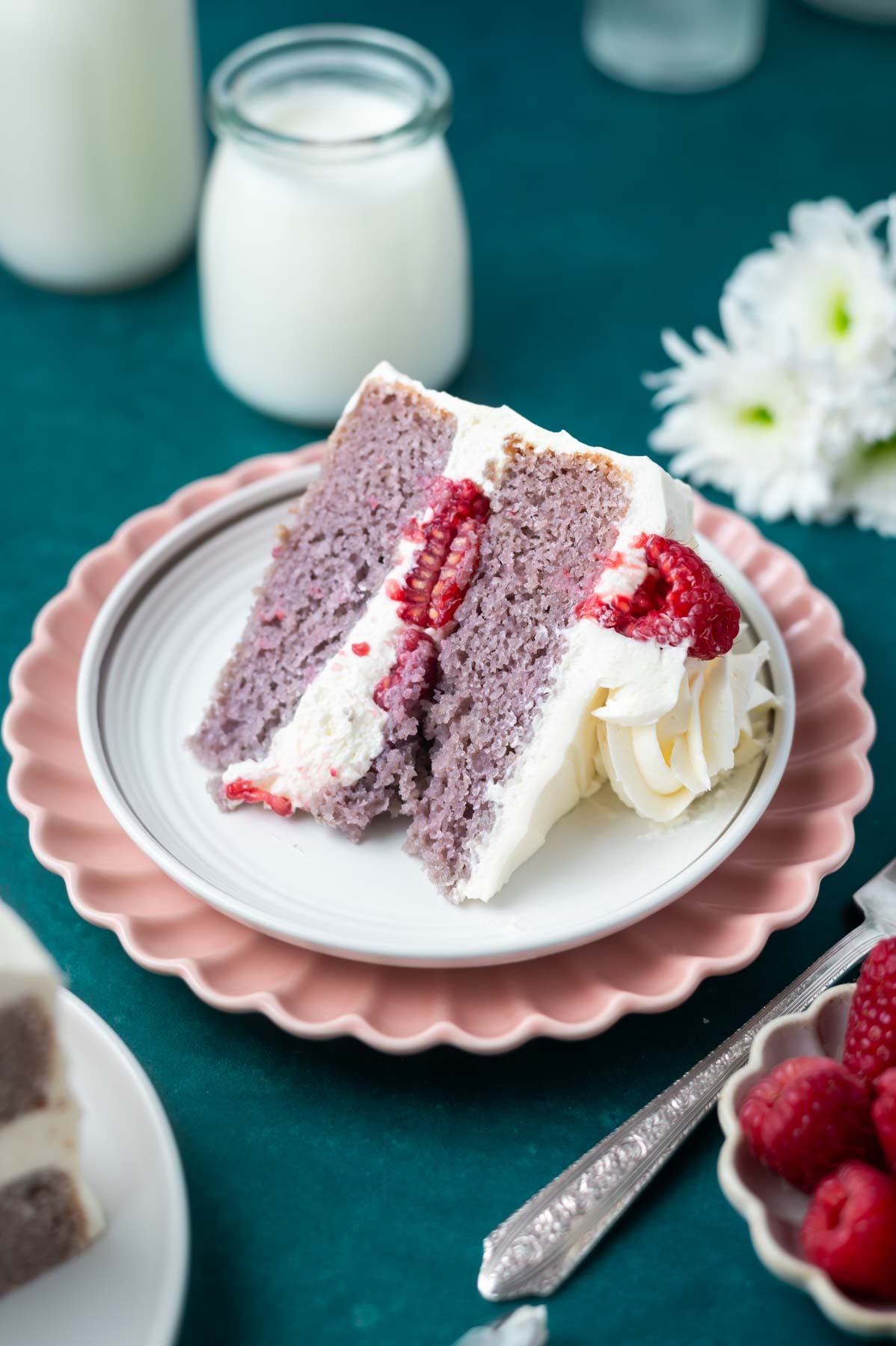 slice of raspberry cake on a plate with milk in the background