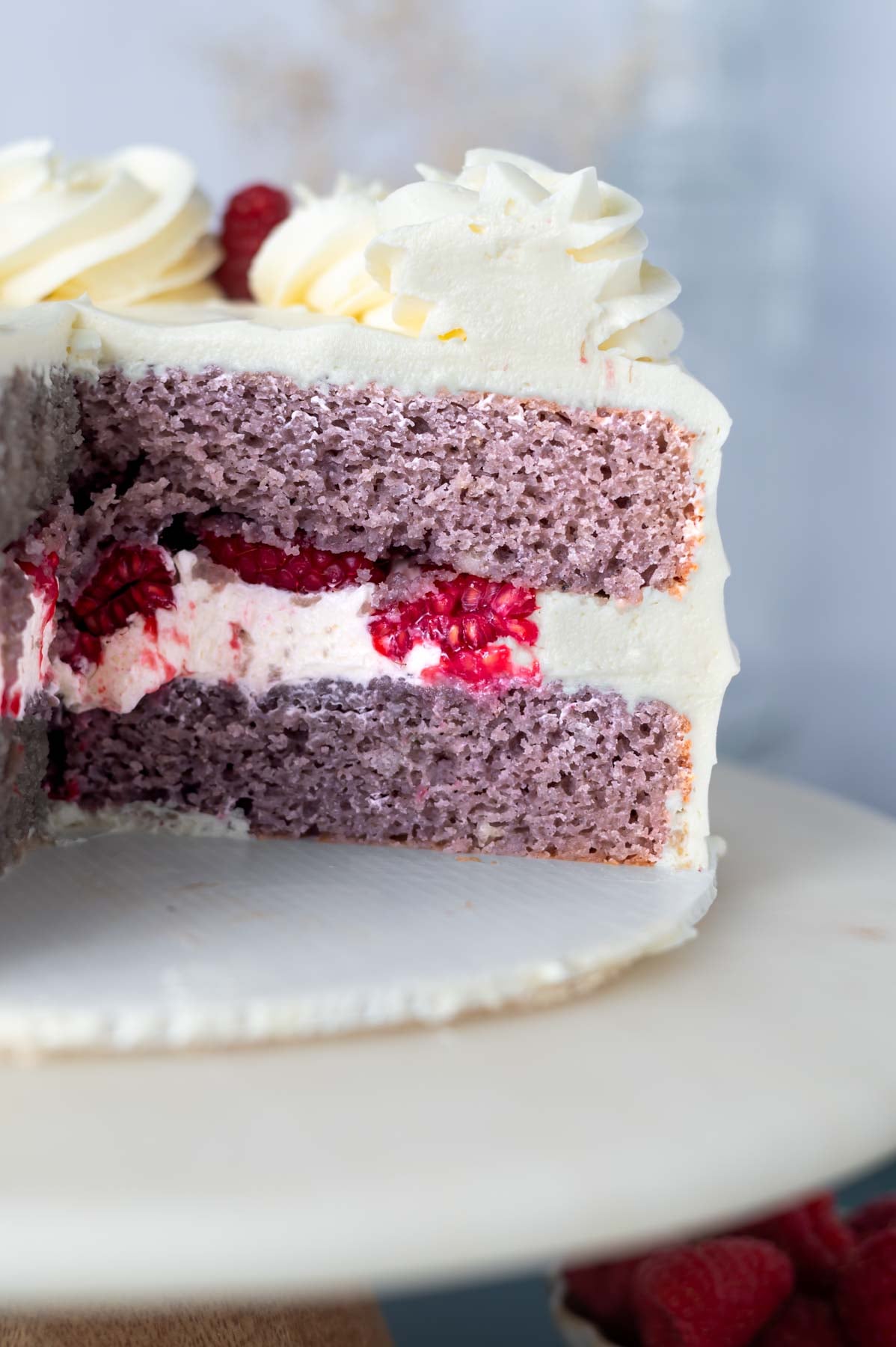 sliced cake on a cake stand showing white chocolate and raspberry filling