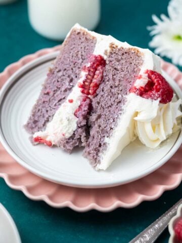 slice of raspberry cake with white chocolate buttercream on a plate