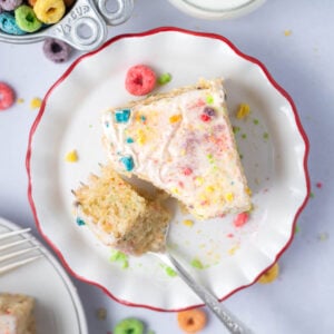 slice of cake on a plate with a bite on a fork and a glass of milk