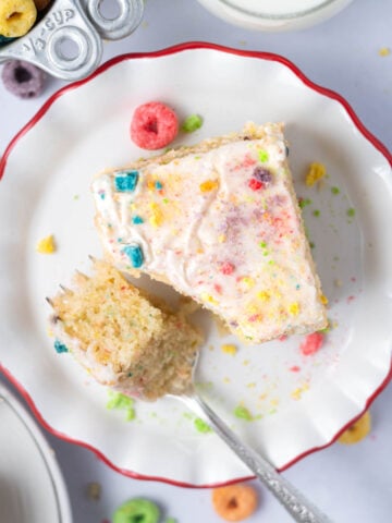 slice of cake on a plate with a bite on a fork and a glass of milk