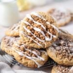 coffee cake cookies piled on a cooling rack with a glass of milk in the background