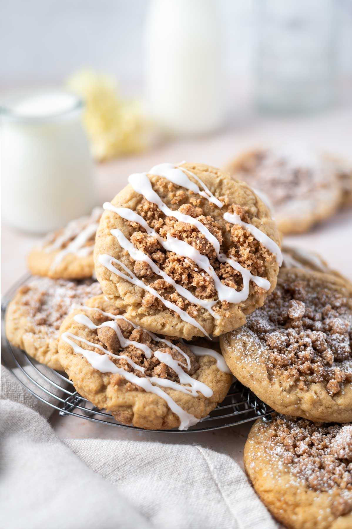 coffee cake cookies piled on a cooling rack with a glass of milk in the background