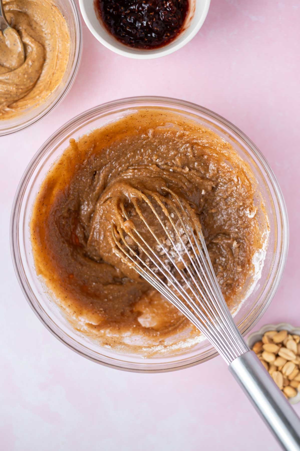 cake batter in a bowl with a whisk with half the flour added
