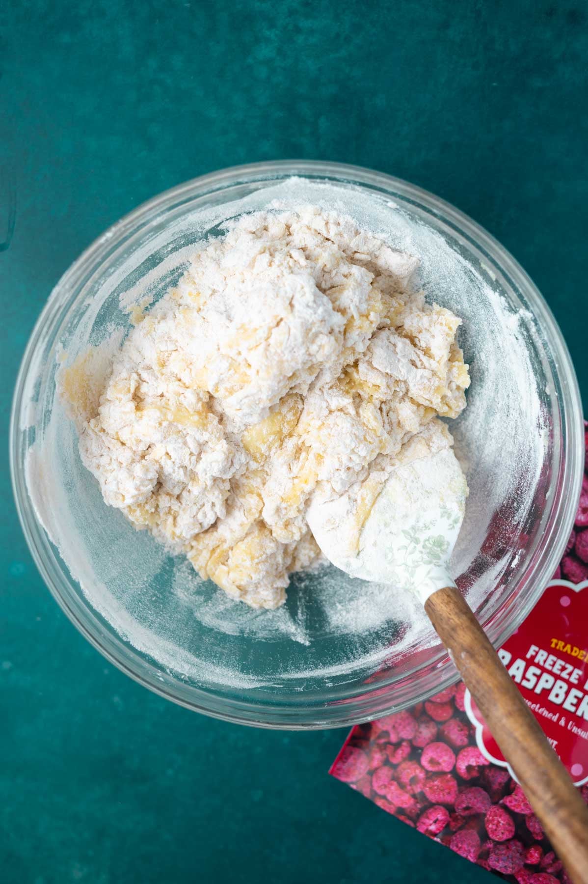 cookie dough with large streaks of flour in a bowl with a spatula