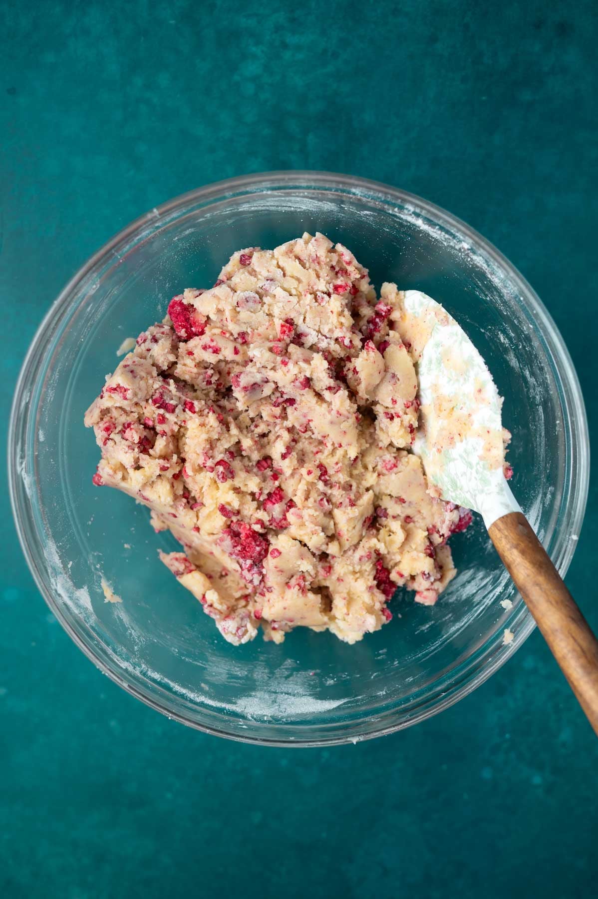 cookie dough in a glass bowl with big pieces of freeze dried raspberries