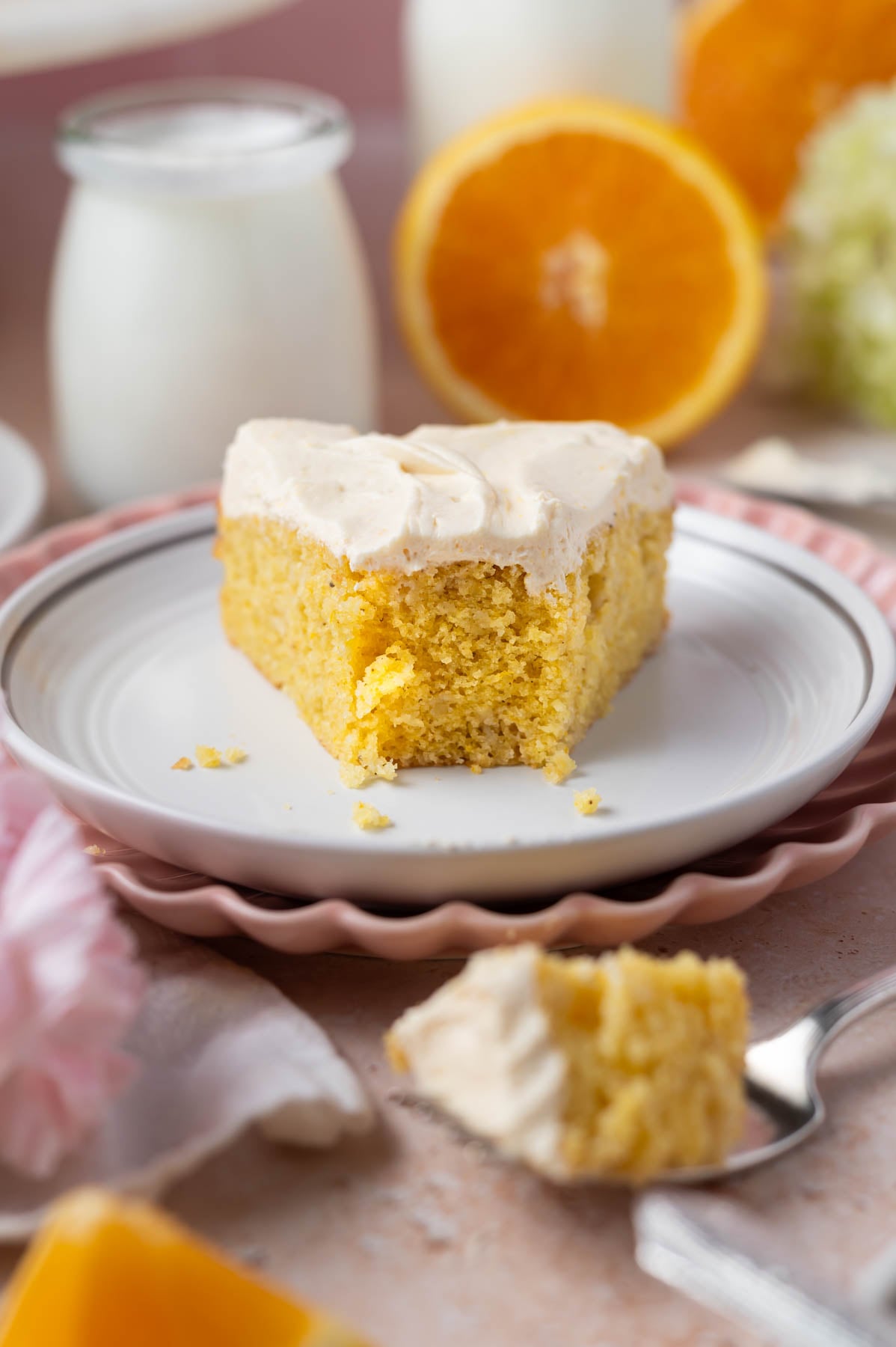 slice of cake on a plate with milk and oranges in the background
