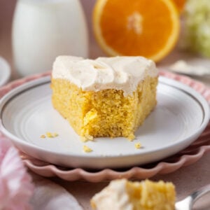 slice of cake on a plate with milk and oranges in the background