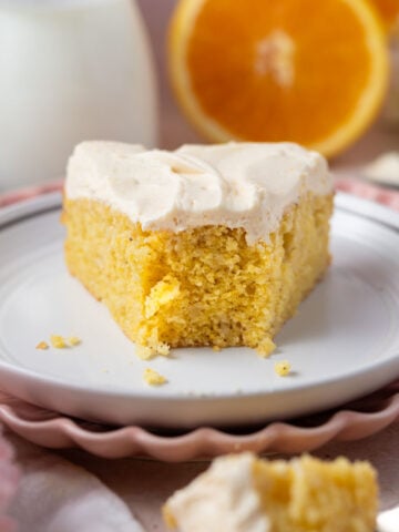 slice of cake on a plate with milk and oranges in the background