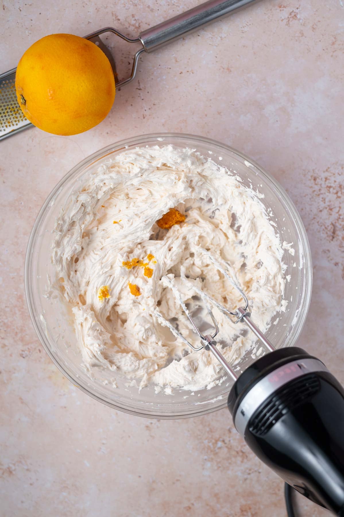 buttercream with orange zest added in a glass bowl