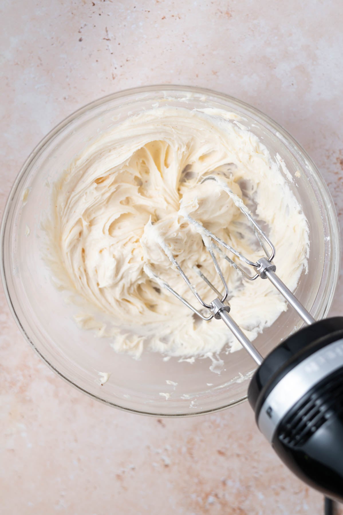 brown butter cream cheese frosting in a bowl with a hand mixer