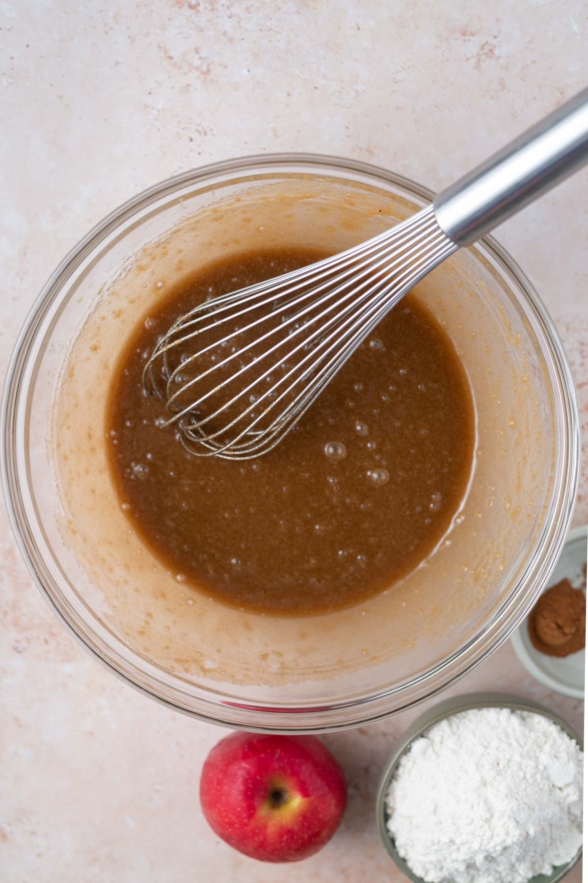 egg and applesauce added to butter and sugars in a bowl with a whisk