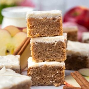 stack of blondies with apples in the background a cinnamon sticks