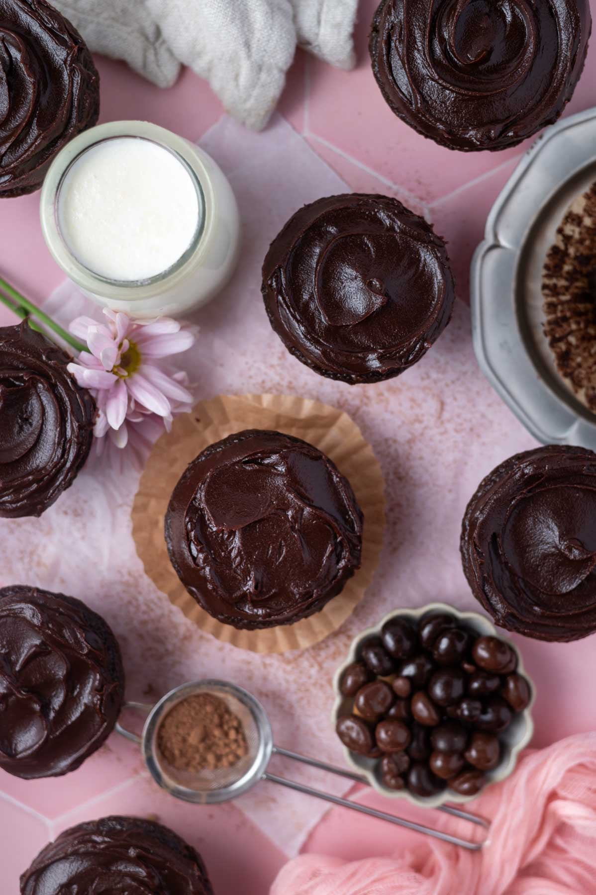 overhead look at silky, soft chocolate ganache frosting on cupcakes with a glass of milk