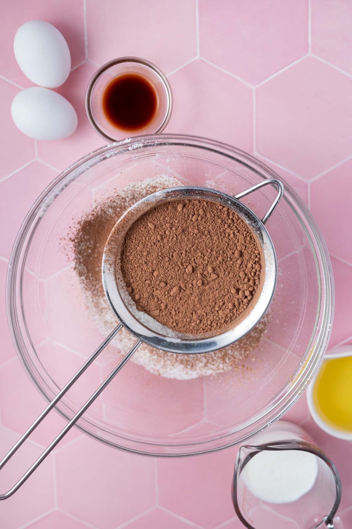 cocoa powder in a sifter over a glass bowl