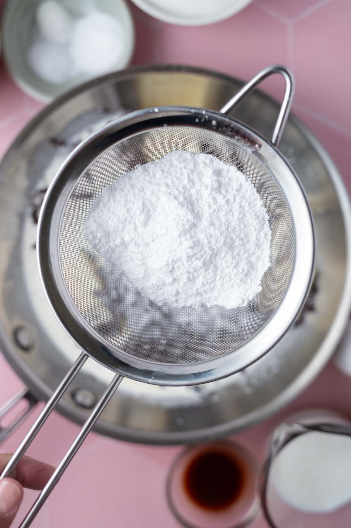 sifter with confectioners' sugar over a skillet
