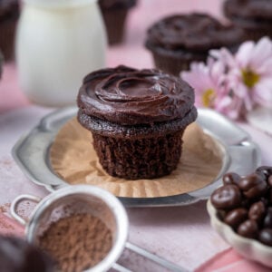 chocolate ganache cupcake on a plate with the wrapper off showing soft crumb