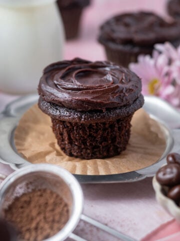 chocolate ganache cupcake on a plate with the wrapper off showing soft crumb