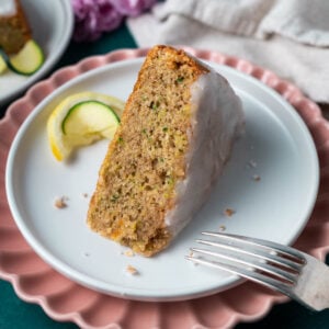 slice of lemon zucchini cake on a plate with a fork and a lemon and zucchini slice