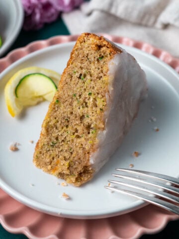 slice of lemon zucchini cake on a plate with a fork and a lemon and zucchini slice