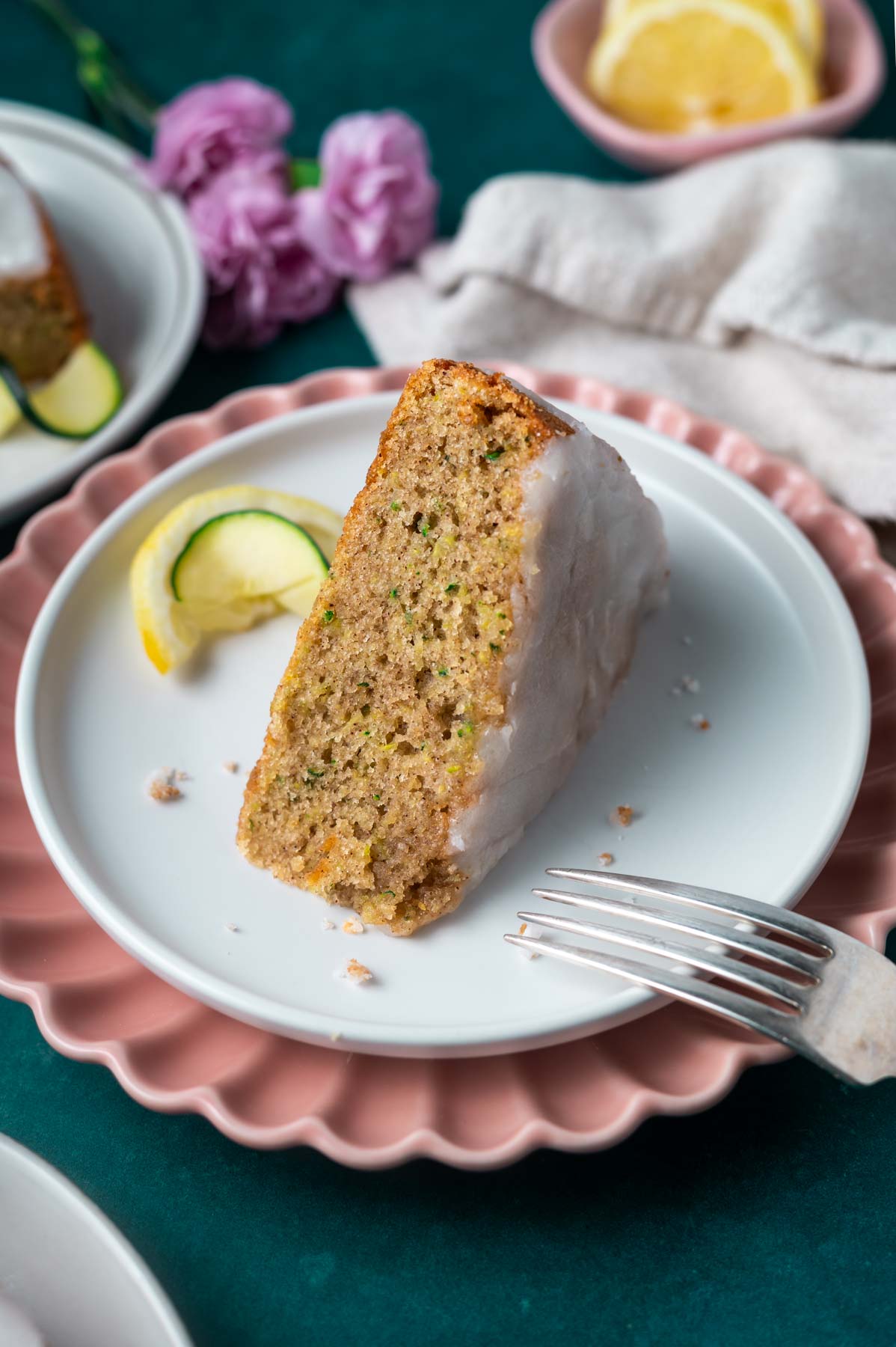 slice of lemon zucchini cake on a plate with a fork and a lemon and zucchini slice