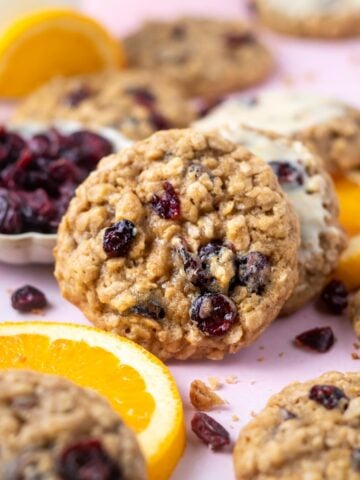 orange cranberry oatmeal cookies with orange slices and a bowl of dried cranberries