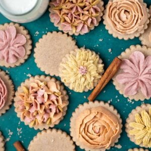 decorated cinnamon sugar cookies with cinnamon sticks and milk on a green counter
