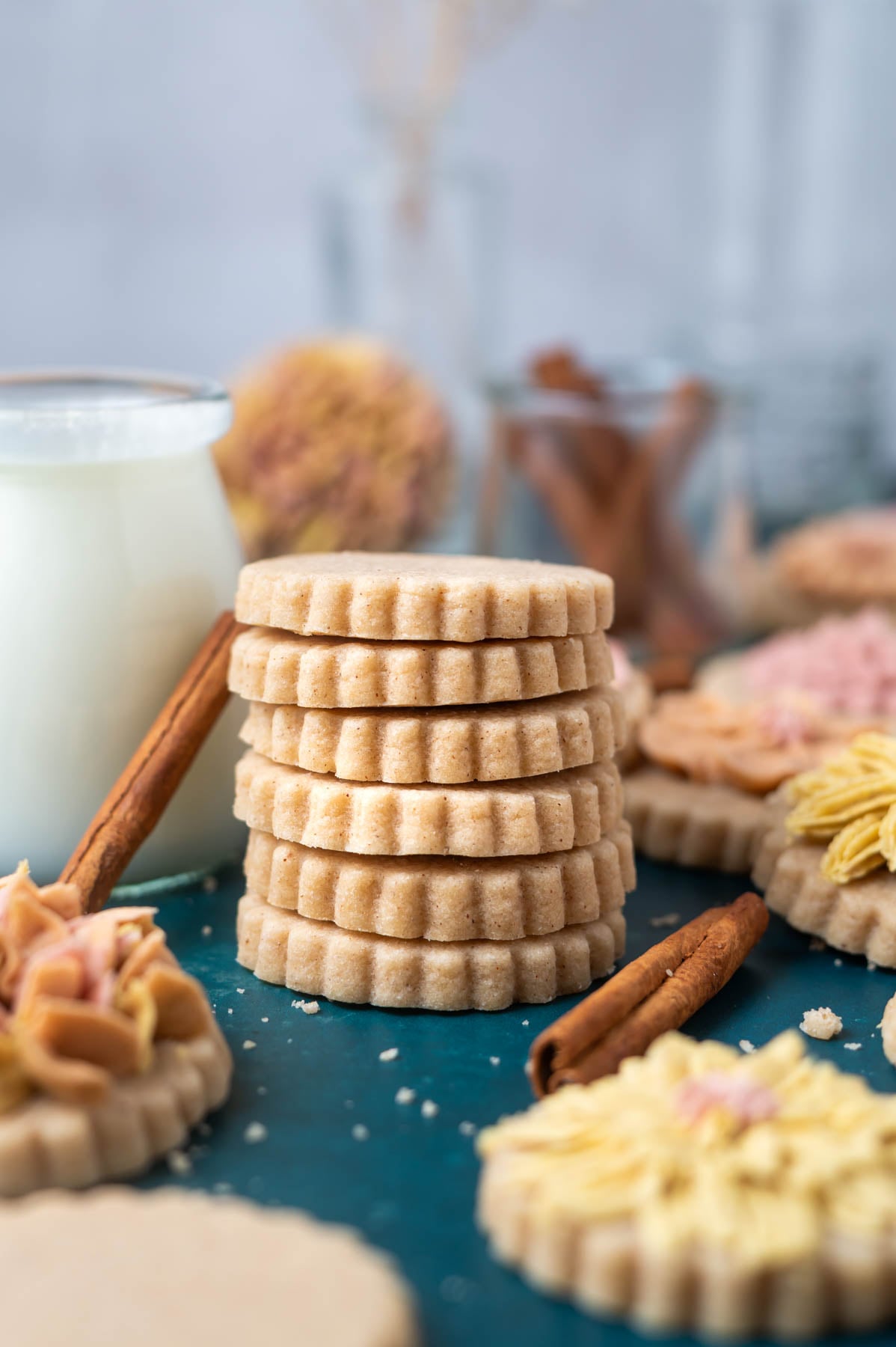 stack of cookies with a glass of milk and cinnamon sticks