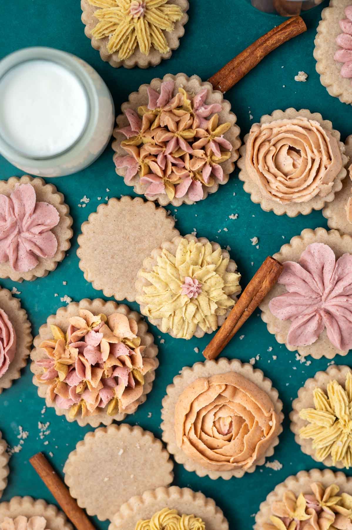 decorated cinnamon sugar cookies with cinnamon sticks and milk on a green counter
