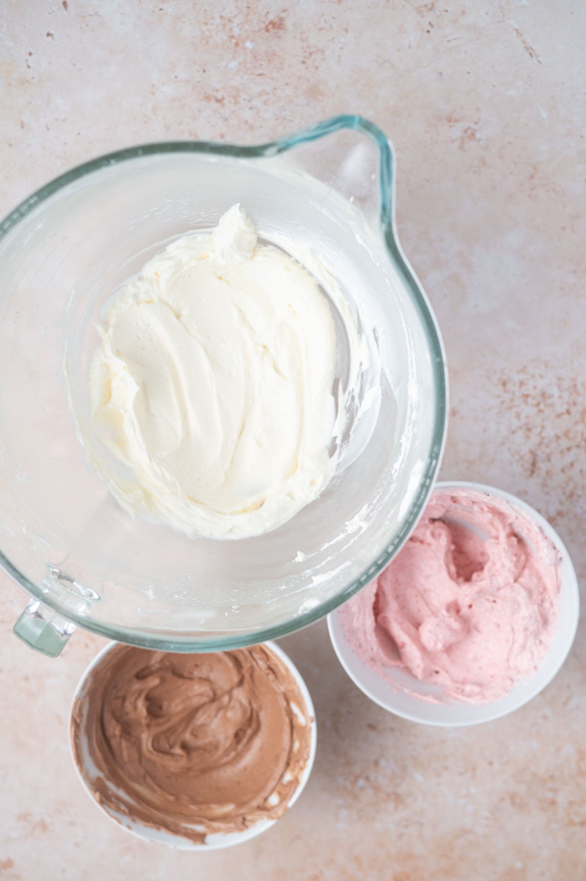 vanilla, strawberry, and chocolate frostings in bowls