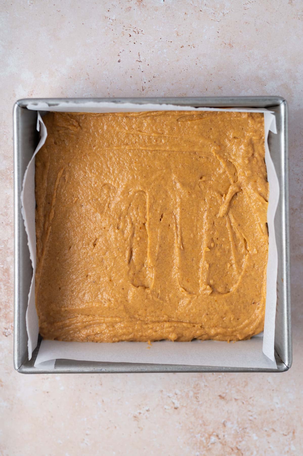 layer of cake batter in a parchment lined baking tin