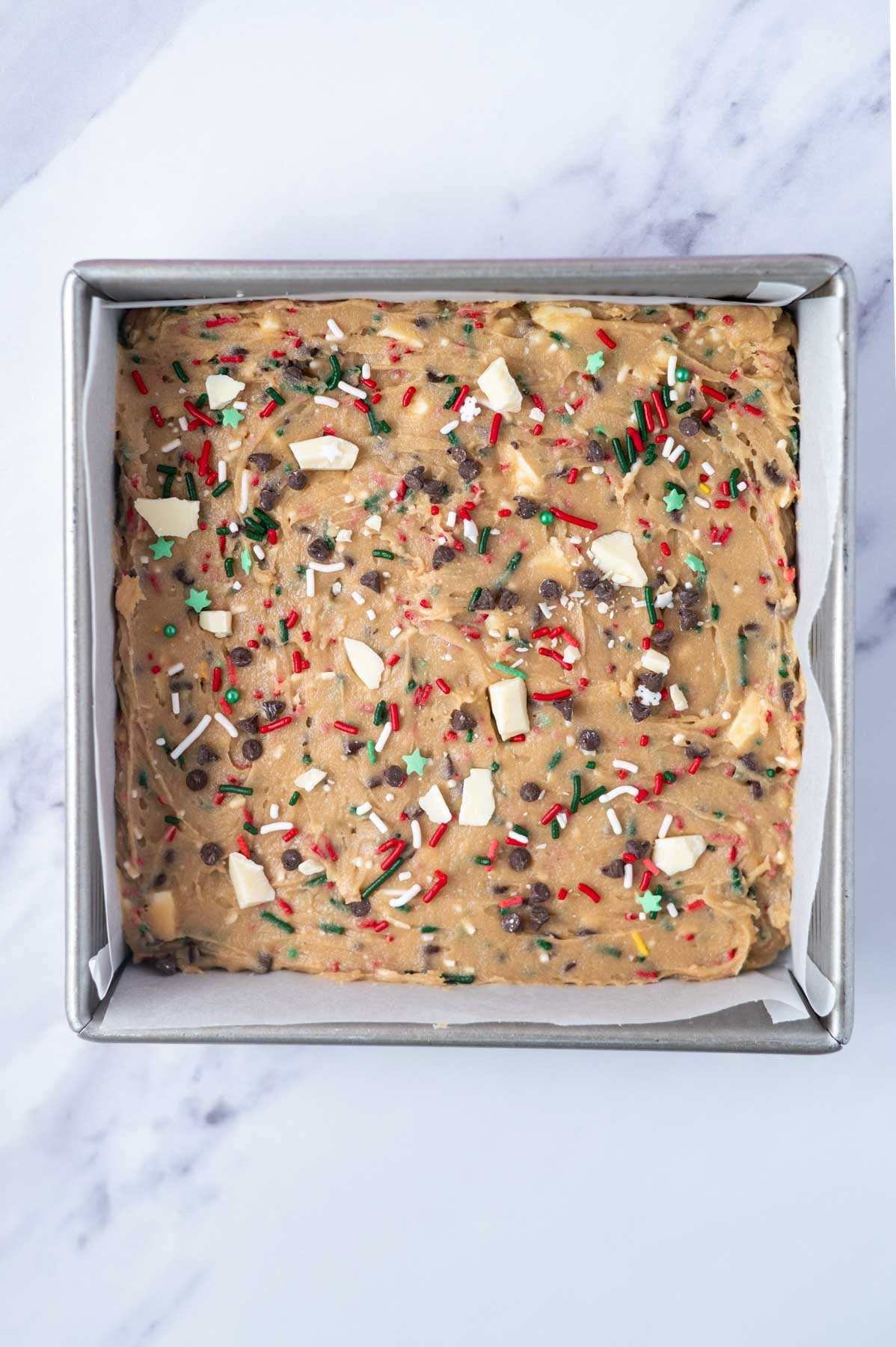 Christmas blondie batter in a parchment lined baking pan