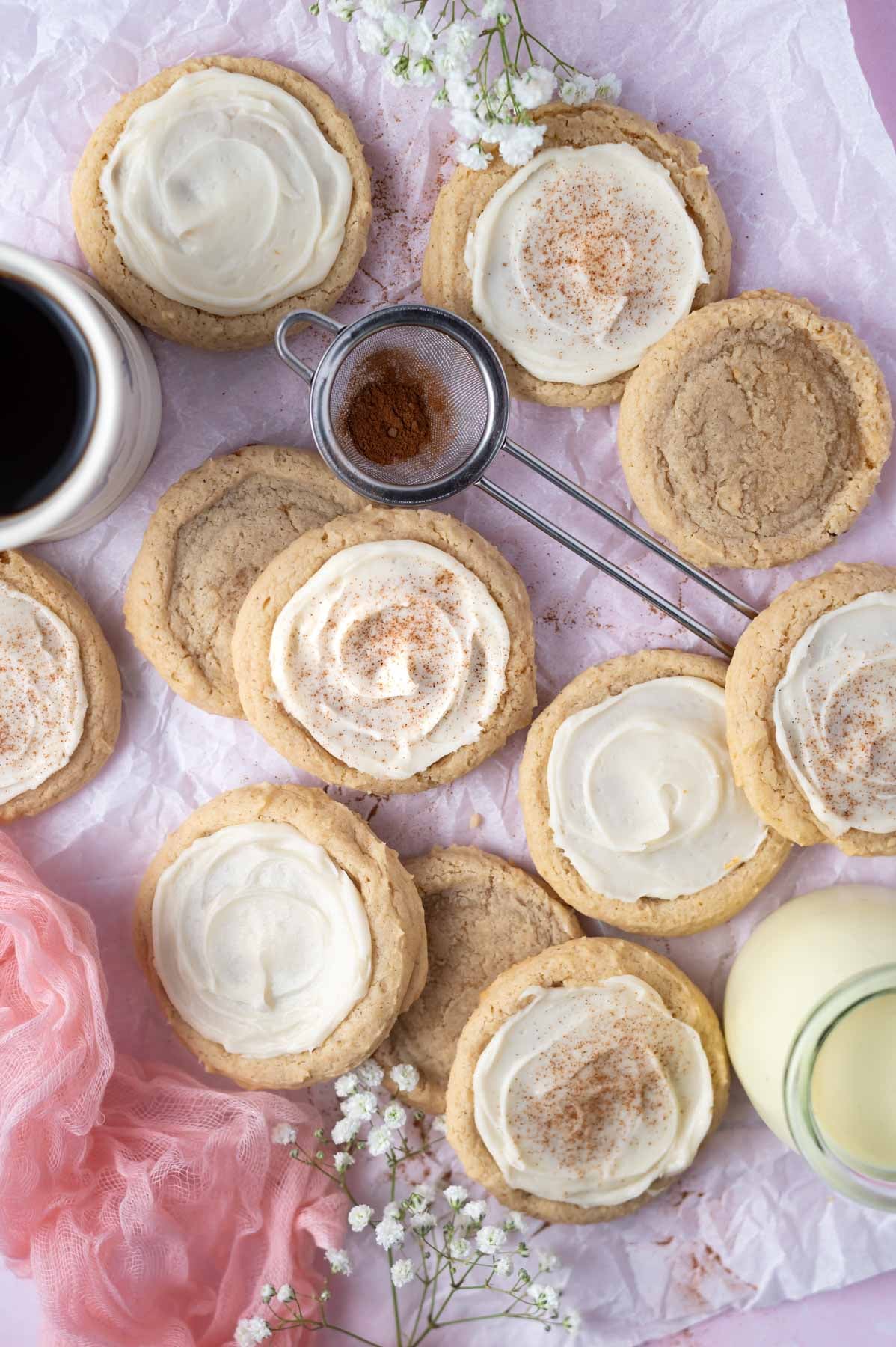 overhead look at frosted cookies on parchment paper with a mug of coffee and babies breath flowers