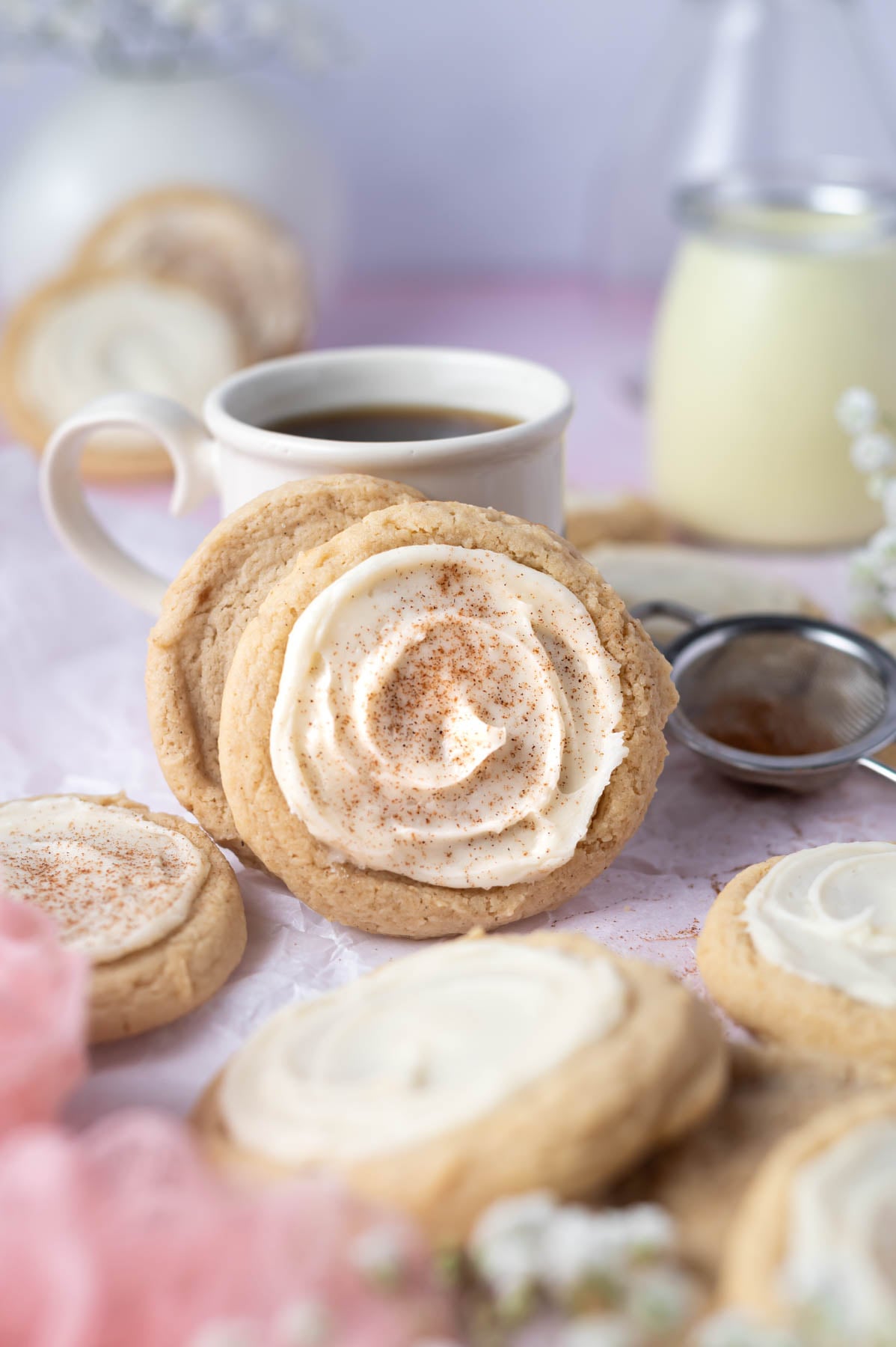 eggnog sugar cookies leaning against a cup of coffee with a glass of eggnog in the background