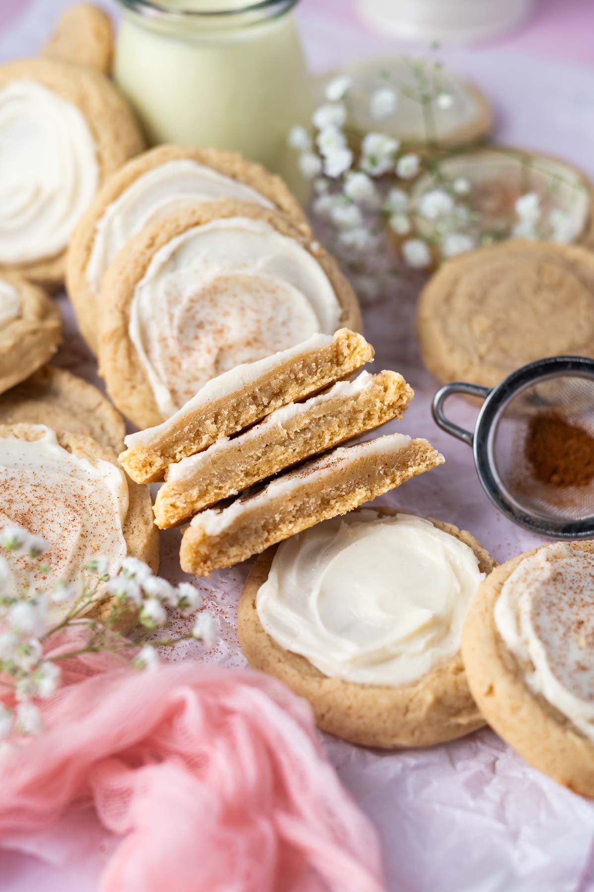frosted cookies on parchment paper with a few broken in half to show the soft inside texture.