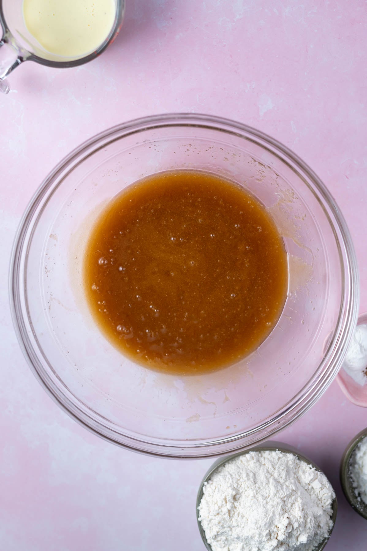 melted butter, sugars and eggs mixed together in a glass bowl