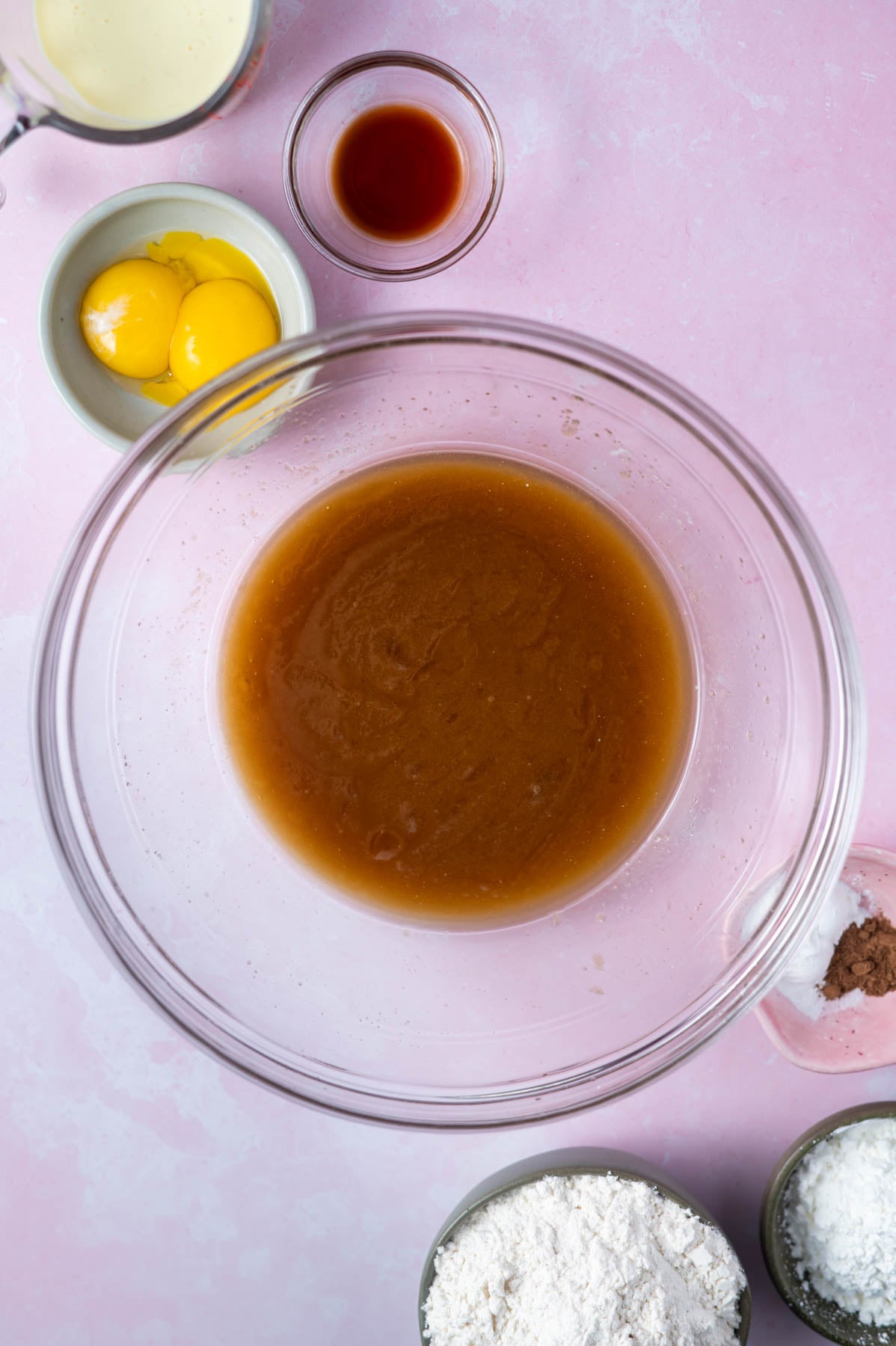 melted butter, brown and white sugar mixed together in a bowl with the remaining ingredients in bowls around the glass bowl