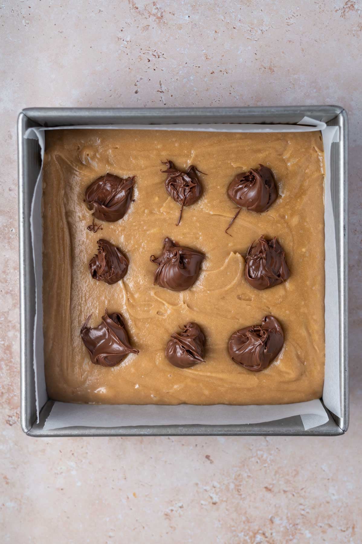 spoonfuls of Nutella over blondie batter in an 8x8 pan